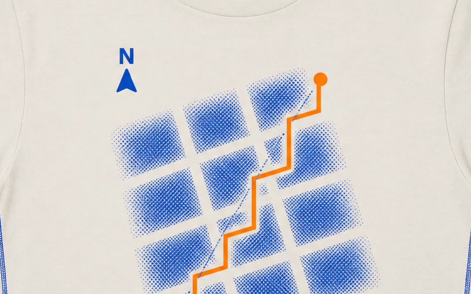 Manhattan Distance, the print up close: bone tee, a tilted Manhattan street grid in cobalt halftone, an orange route up the streets and a north arrow